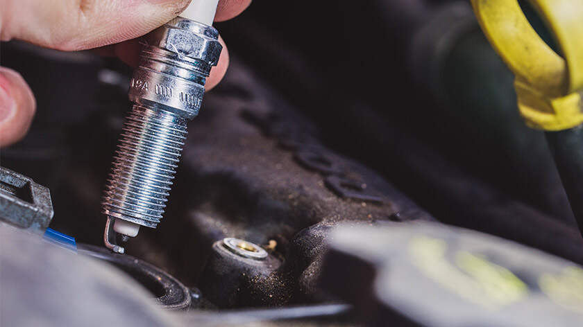 A close-up of a person's hand holding a spark plug